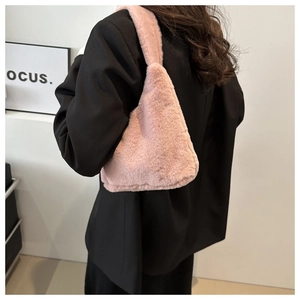 Detail view of pink plush faux fur tote bag carried by model wearing a black blazer