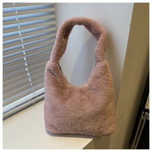 Close-up of the soft dusty rose faux fur texture and curved handle of this plush handbag