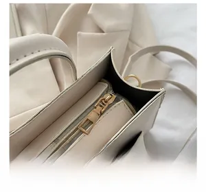 Detail of light gold metal zipper on cream white handbag with pebble leather texture