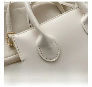 Detail of meticulous stitching and matte leather texture on a beige tote handbag