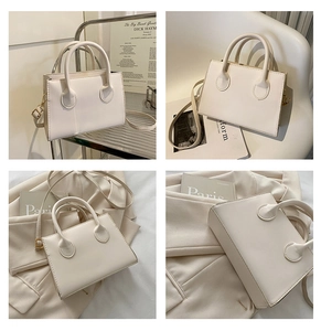 Detail view of a cream leather crossbody bag with round handles and gold hardware