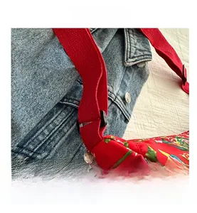 Detailansicht der roten Umhängetasche mit Blumenmuster und verstellbarem Textilgurt