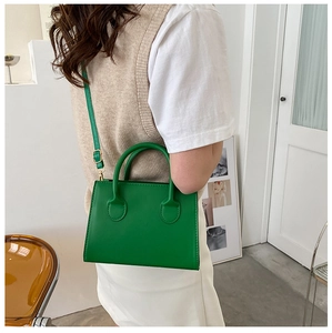 Detail showing the adjustable shoulder strap and smooth faux leather of the green handbag