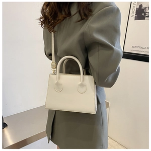 Side view of a minimalist white crossbody bag with adjustable strap on a model
