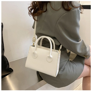 Minimalist white faux leather handbag detail with round handles and gold hardware