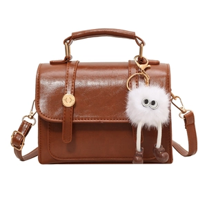 Vintage brown leather crossbody bag with a gold buckle and cute plush doll pendant