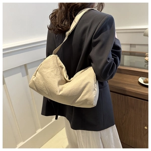 Detail view of the beige canvas pillow bag featuring soft texture and wide shoulder strap
