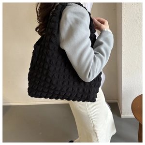 Close-up of black bubble textured tote bag with thick shoulder strap on model