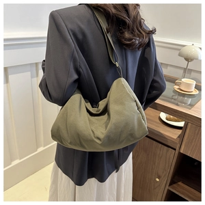 Detail view of military green pleated crossbody bag on model in a cozy cafe setting