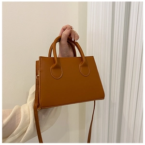Close-up of a brown textured leather handbag with top handles and shoulder strap