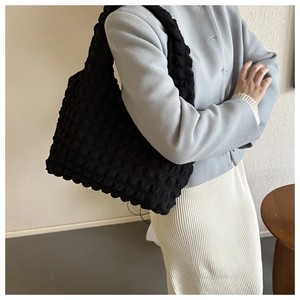 Close-up of black popcorn texture tote bag worn by model with minimalist stitching detail