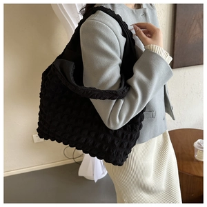 Detail of black bubble textured tote bag with pleated straps and soft padded material