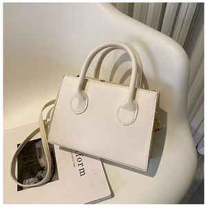 Detailed view of cream PU leather mini square bag with golden hardware on a white chair