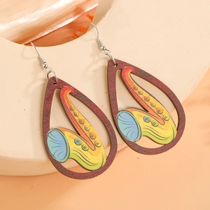 Détail de boucles d'oreilles en bois en forme de goutte avec motif de saxophone coloré