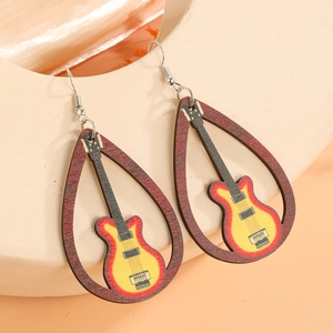 Détail de boucles d'oreilles en bois en forme de larme avec motif guitare sur un support