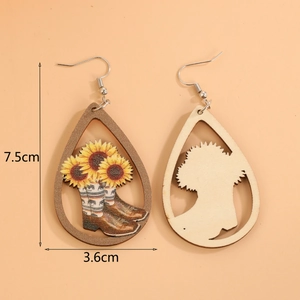 Detail of wooden teardrop earrings with sunflower and cowboy boot prints on orange background