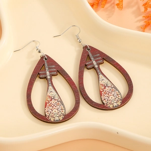 Détail de boucles d'oreilles goutte en bois avec motif floral sur plateau étoilé