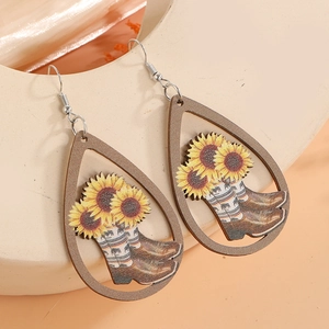 Detail of wooden teardrop earrings with sunflower and western cowboy boot motifs