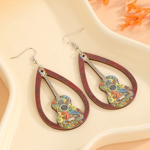 Détail de boucles d'oreilles bohèmes en bois avec pendentif guitare coloré sur plateau céramique