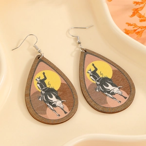 Detail of teardrop earrings featuring western cowboy bull riding scene on a ceramic tray