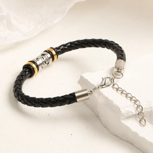 Detalle de pulsera de cuero trenzado con calavera plateada y detalles dorados