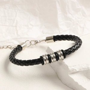 Vista detallada de pulsera de cuero trenzado negro con cuentas de metal plateado