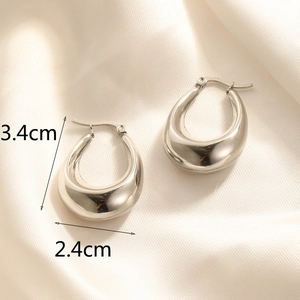 Detailed view of polished hoop earrings measuring 3.4cm by 2.4cm on silk fabric