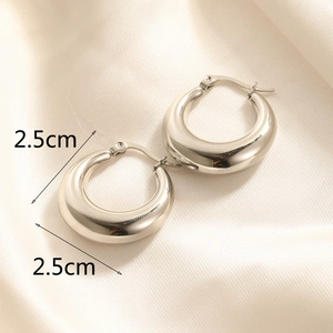Macro shot of polished 2.5cm silver stainless steel hoop earrings on satin fabric