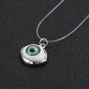Macro shot of realistic green eye pendant with silver frame on transparent fishline cord
