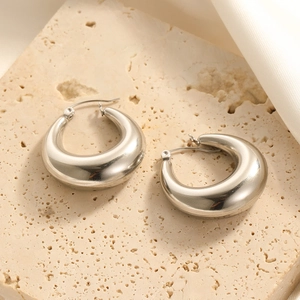 Polished silver chunky puffed hoop earrings displayed on a minimalist stone base