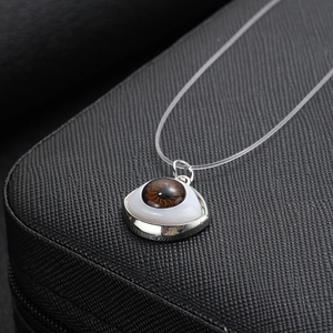 Detailed close-up of a realistic evil eye pendant on a transparent fishing line necklace