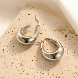 Minimalist silver teardrop hoop earrings in polished stainless steel on stone texture