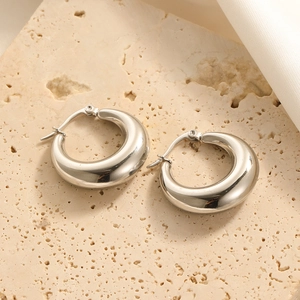 Close-up of chunky silver stainless steel hoop earrings with a mirror polished finish