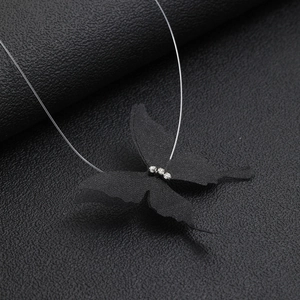 Detail of a black tulle butterfly pendant with three rhinestones on a clear invisible chain