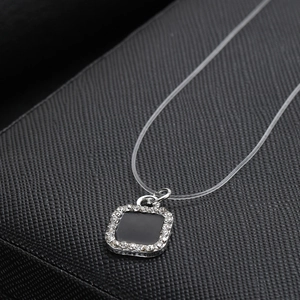 Detalle del colgante cuadrado de esmalte negro con cristales en collar de hilo invisible