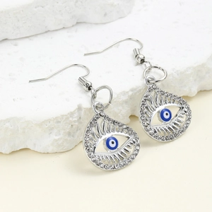 Macro detail of silver drop earrings with blue evil eye charm and sparkling crystals