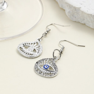 Macro shot of silver evil eye drop earrings with blue enamel and sparkling rhinestones
