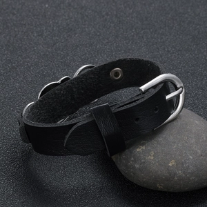 Gothic skull leather bracelet with silver heart charm on natural stone background