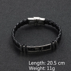 Macro shot of a black braided leather bracelet featuring a stainless steel cross charm
