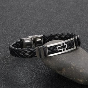 Men's woven leather bracelet with stainless steel cross plaque on a textured stone