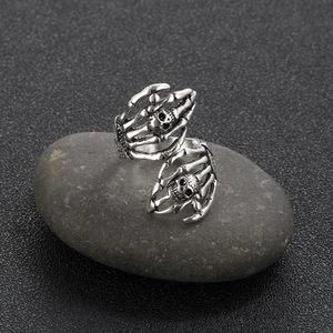 Close-up of retro punk skull hand ring with vintage silver finish on pebble