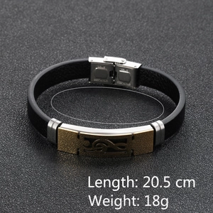 Detail of men's leather bracelet with golden music note plate and stainless steel clasp