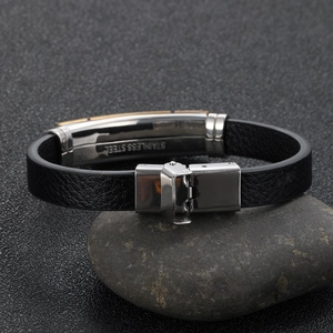 Men's leather bracelet with a gold-tone stainless steel musical note clasp on a dark stone