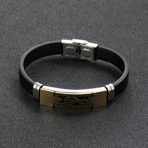 Men's leather bracelet with golden music note stainless steel charm on grey background