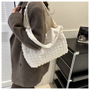 Detail of white quilted bubble fabric tote bag showing soft texture and wide strap