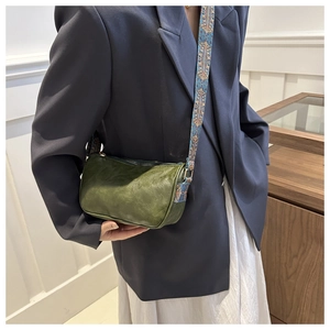 Close-up of retro green Boston bag featuring a colorful ethnic style woven wide strap