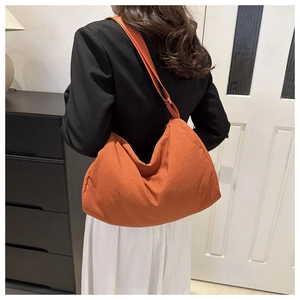 Caramel crescent crossbody bag with adjustable wide strap shown on a model's back