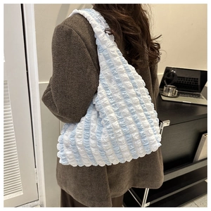 Detail of the blue and white seersucker textured tote bag on a model's shoulder