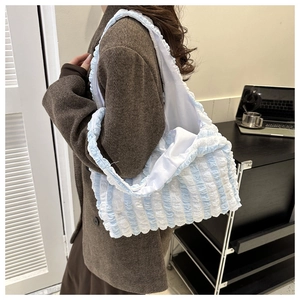 Detailed texture of blue and white striped puffy tote bag worn by a model in casual setting