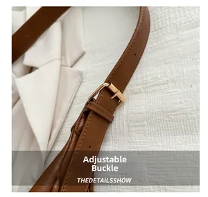 Details eines verstellbaren braunen Lederriemens mit goldener Metallschnalle für Taschen
